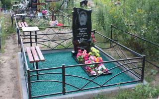 Памятник из гранита с лавочкой и металлической оградой, могила украшена декоративным щебнем